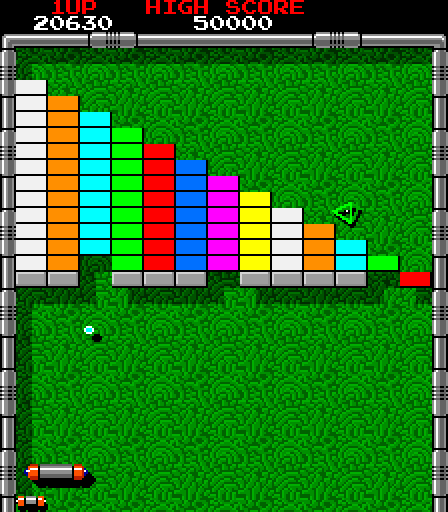 Screenshot of Arkanoid. The player controls a suspiciously paddle-looking spaceship in the lower left. Most of the screen shows colorful bricks arranged in a staircase pattern against an abstract green background. One enemy hovers menacingly, a green hollow tetrahedron with a shiny black core.
