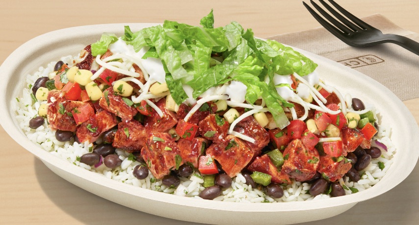 Photo of a Chipotle burrito bowl. The single-use, elliptical bowl contains chicken al pastor, corn, cheese, sour cream, lettuce, black beans, and cilantro lime white rice.