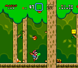 Screenshot from Super Mario World shown at double its native 256x224 resolution. Wearing a yellow cape, Mario is riding Yoshi in a dense forest, flanked by a hovering Goomba, a shell-less Koopa, and an obscured Wiggler.